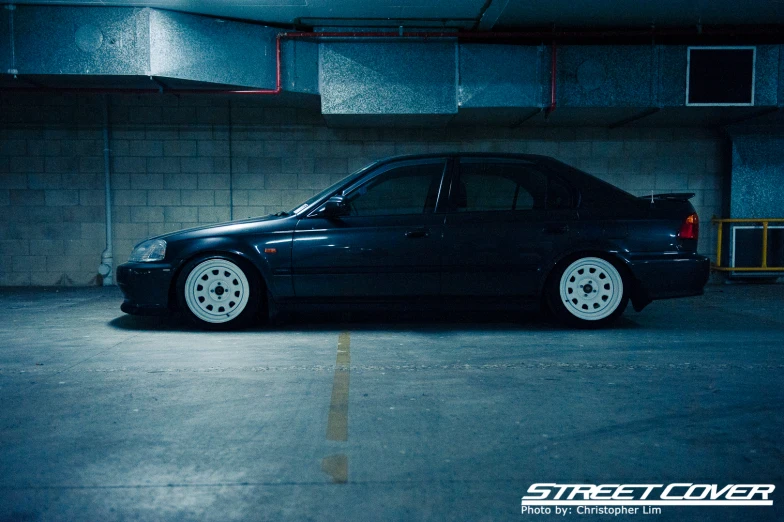 a black car parked in a garage with the back lights on