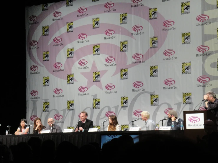 a panel of people at an event talking on a stage