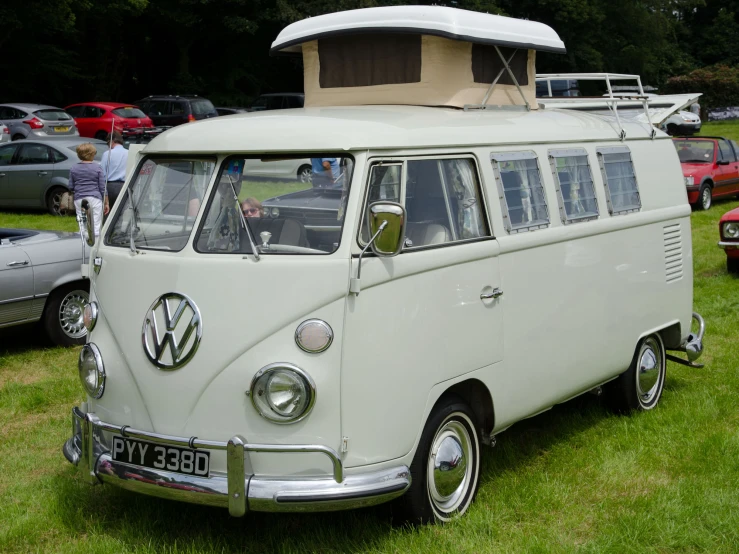 an old vw bus sits parked on the grass