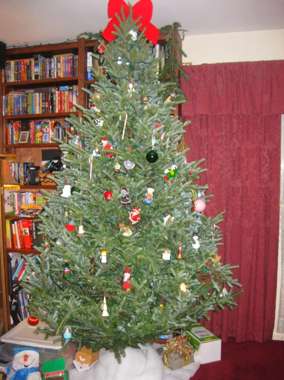 the green tree in the living room is decorated for christmas