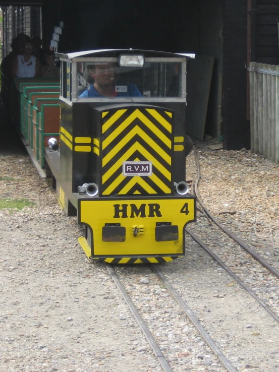 the caboose has a man standing inside and there is a small train approaching
