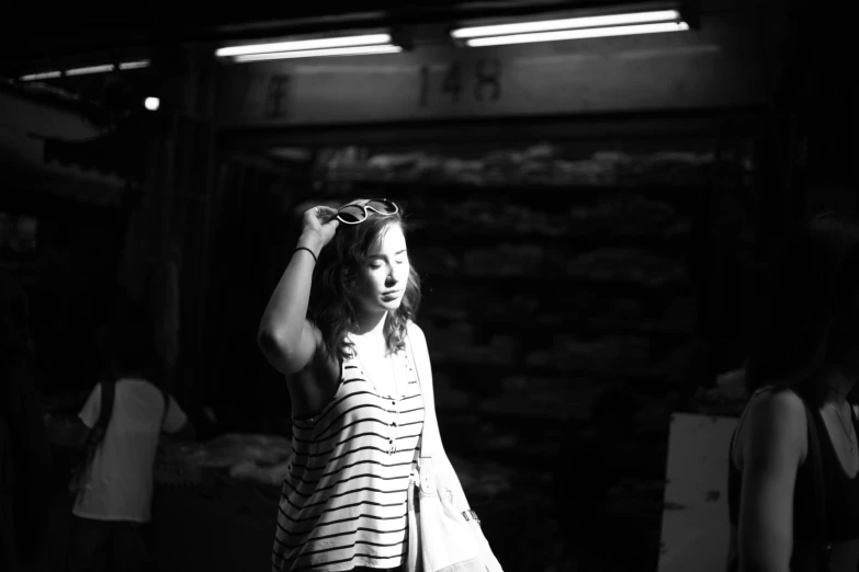 a woman holds a pair of sunglasses as she walks through an outdoor market