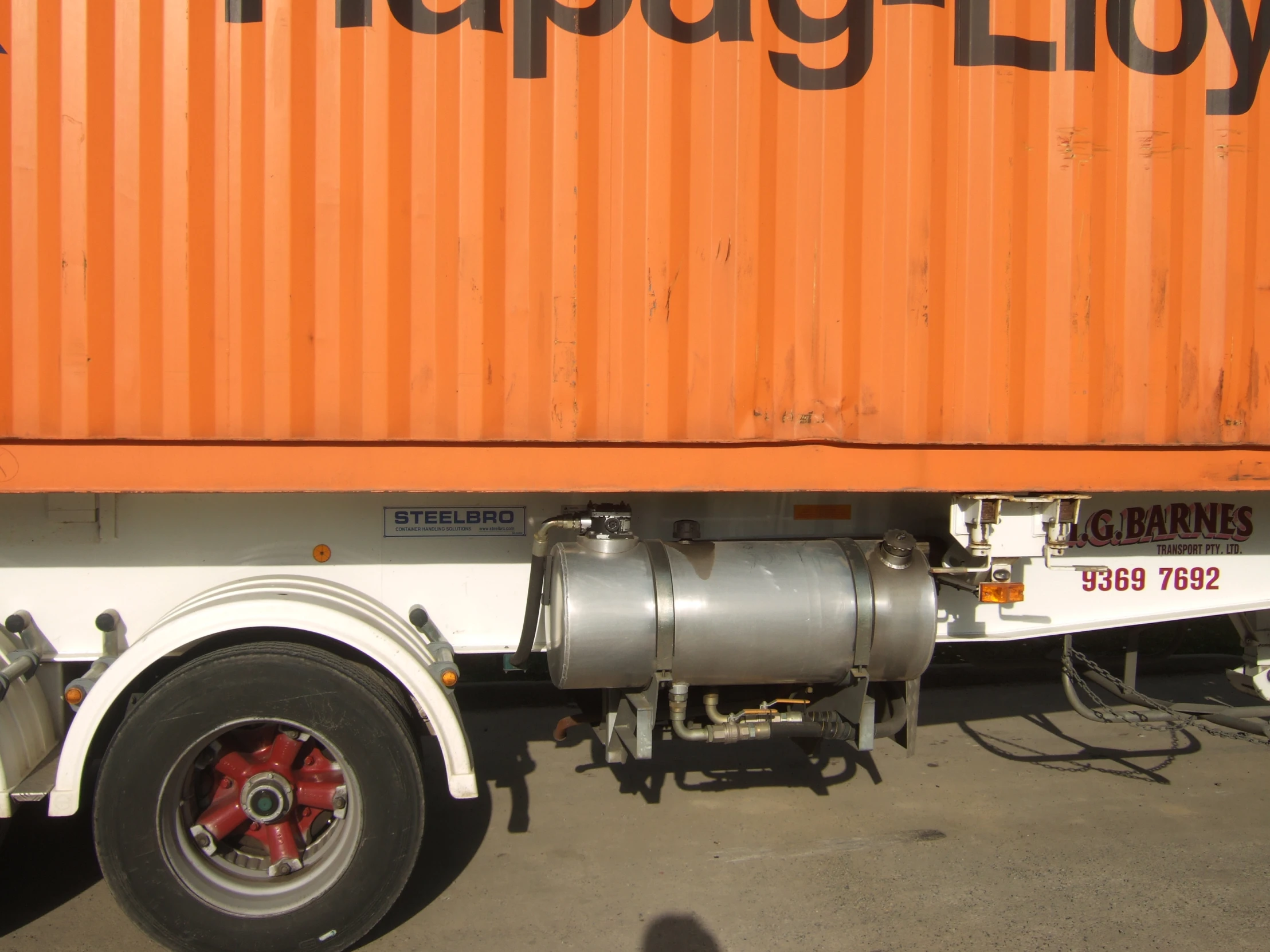 large orange box truck parked behind an industrial trailer