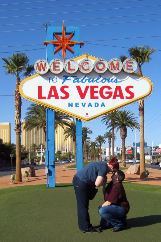 a man and a woman sitting under a large welcome sign