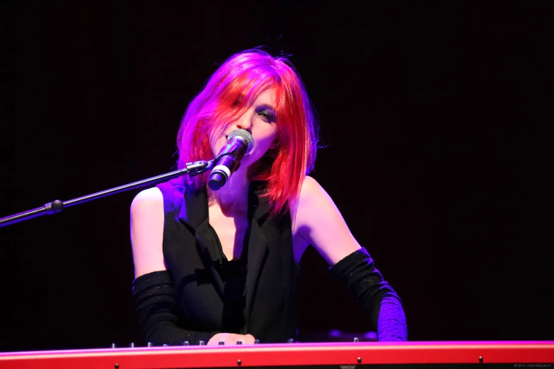 a red headed woman in an outfit sings into a microphone