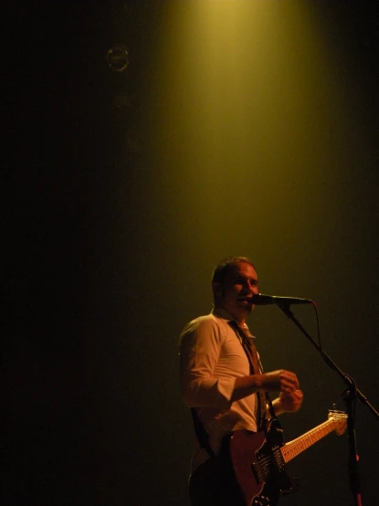 a male in a white shirt is playing the guitar