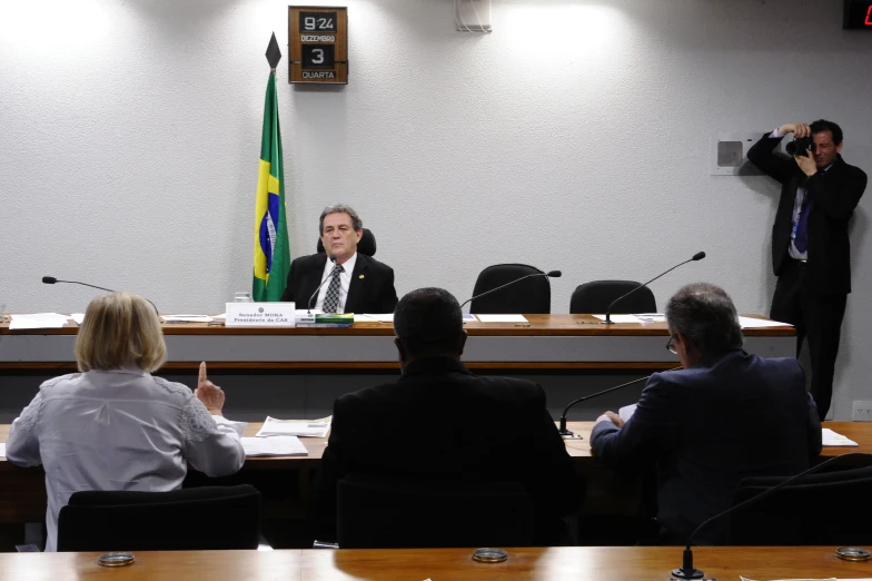 several people sitting around a table in front of a speaker