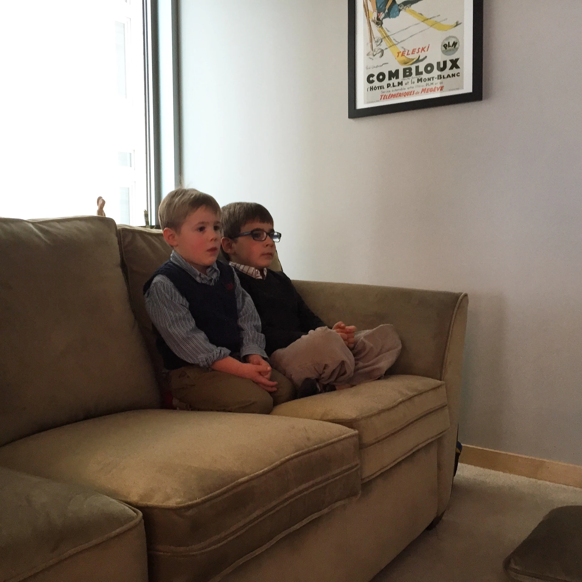 a woman and a boy sit on a brown couch