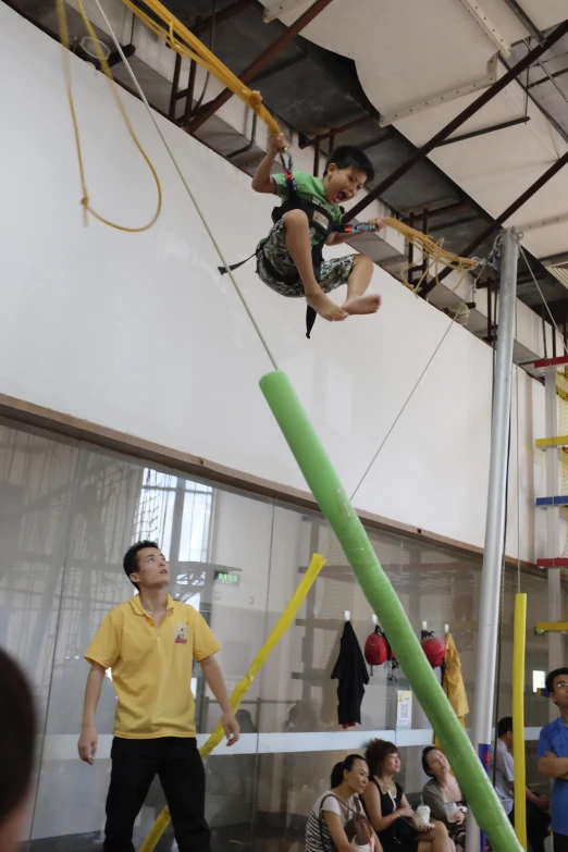 man with green shirt standing on ropes while people watch