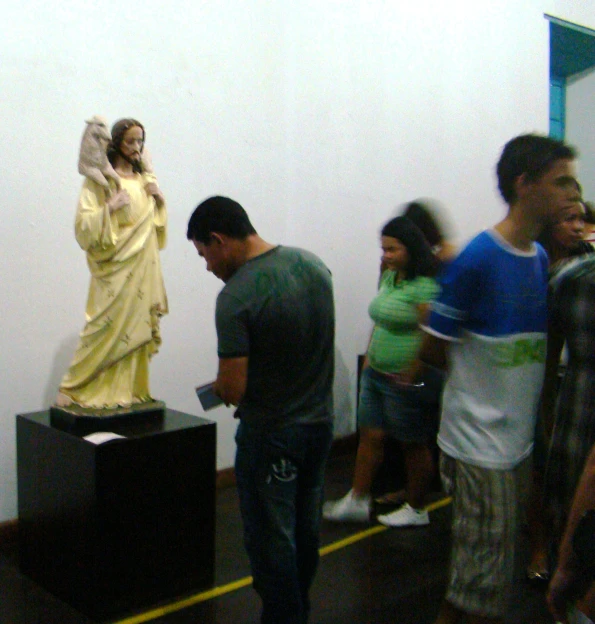 several people stand around a statue on a pedestal