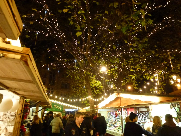 many people walk around in the marketplace with many lights