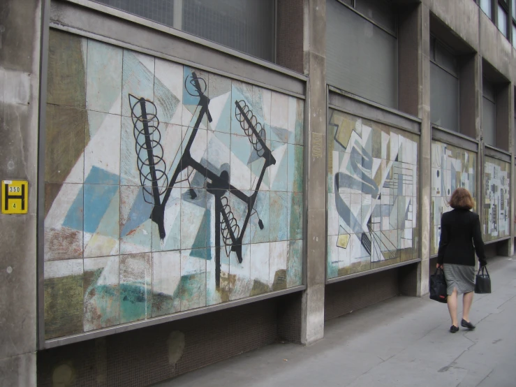 the woman is standing by some interesting artwork on a wall