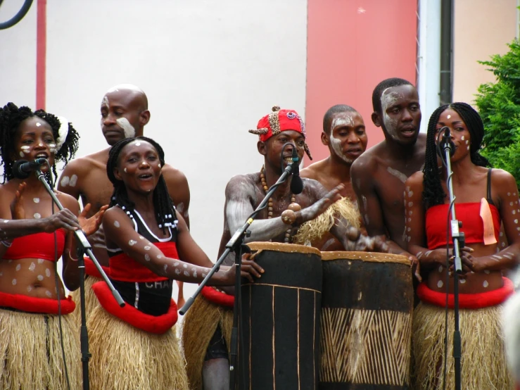 four men are dressed in native style clothing with large sticks