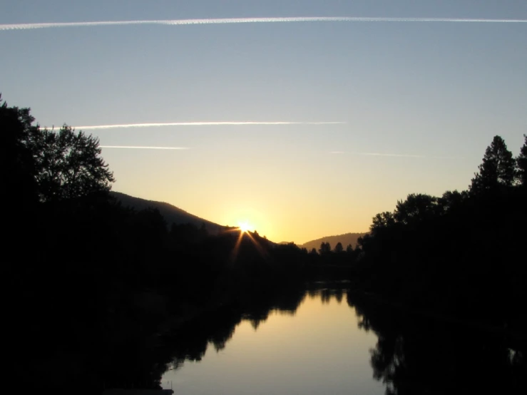 the sun rises over the mountain range as water reflects its image in the reflection of the clouds