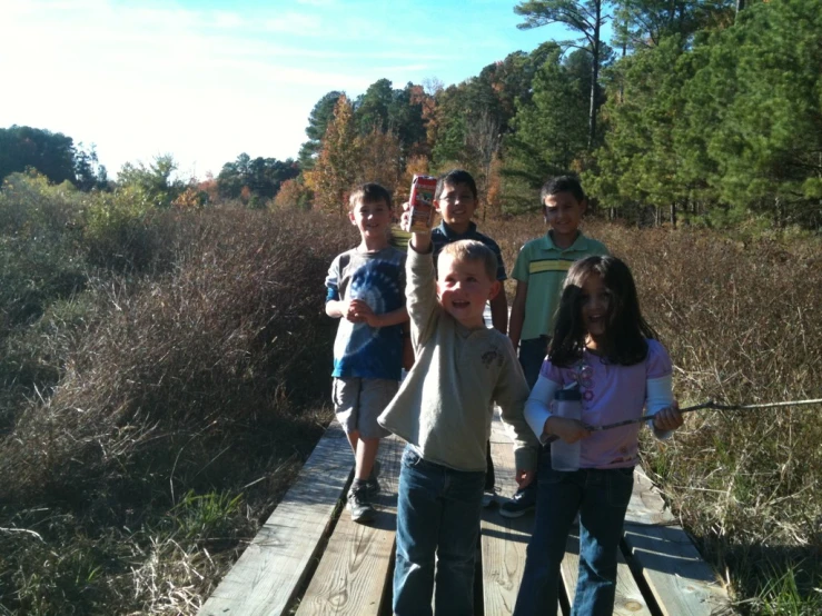 a group of s standing on a bridge that goes through some grass