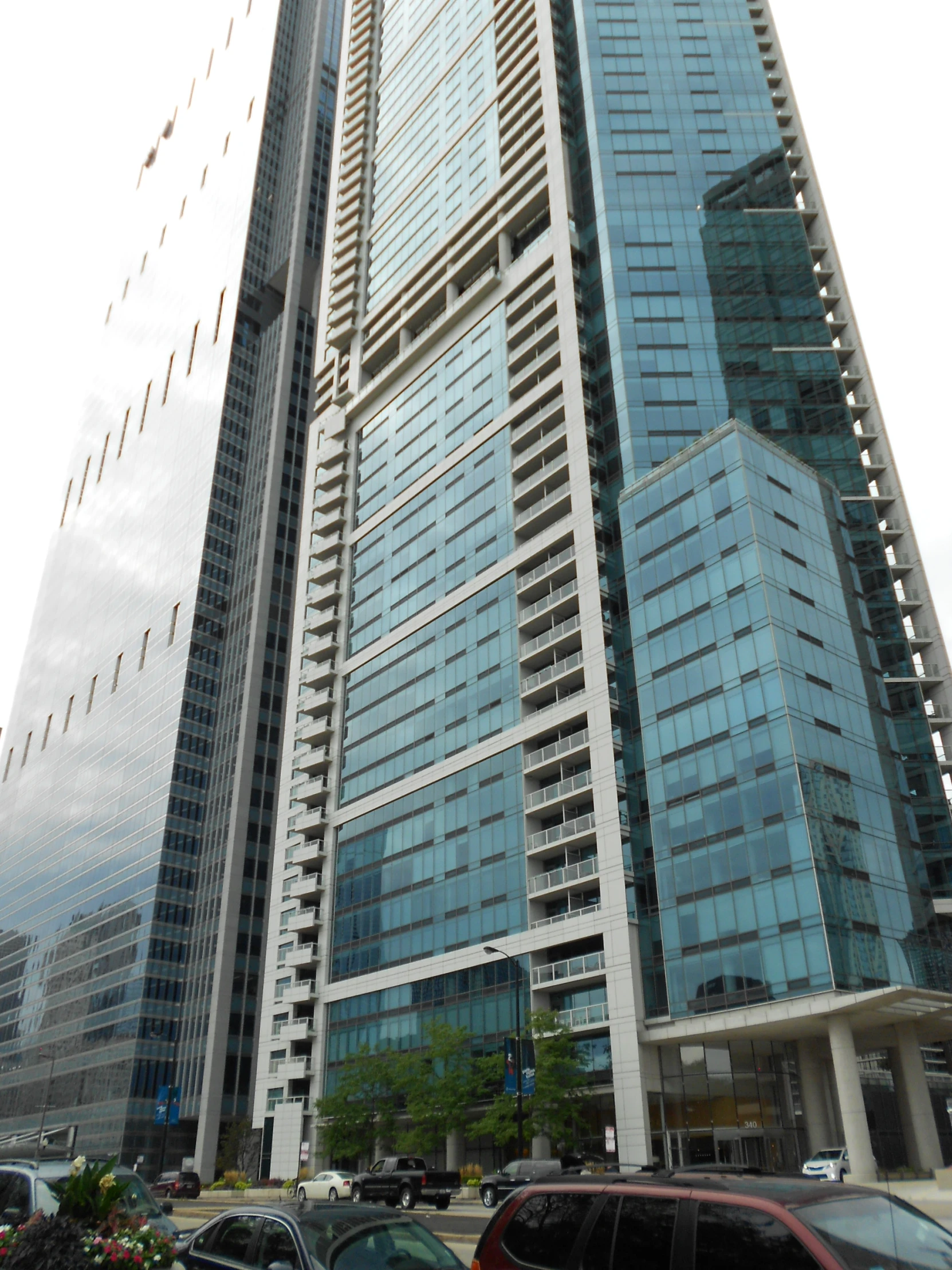 tall, glass office building on a city street with various vehicles parked