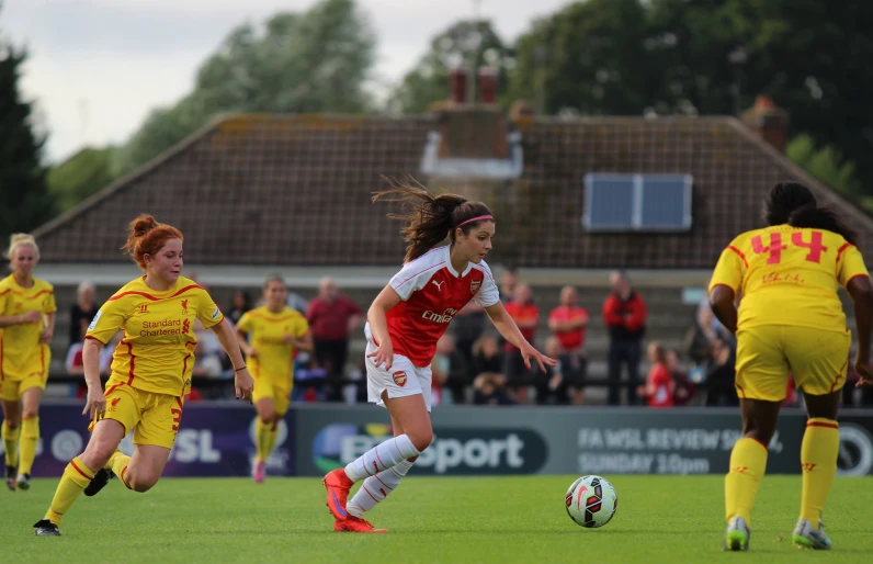 female soccer players in uniforms are playing on the field