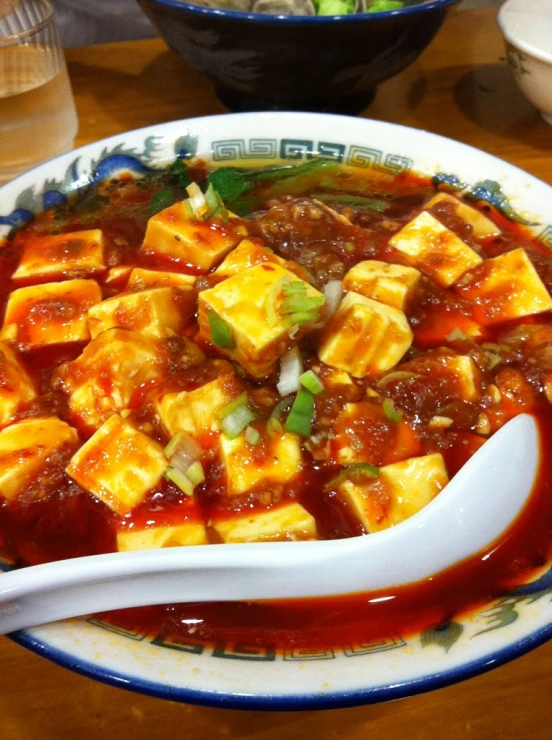 a plate with tofu, sauce and a spoon