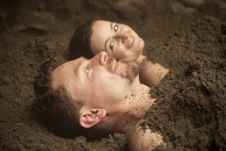 two young men laying on a dirt ground