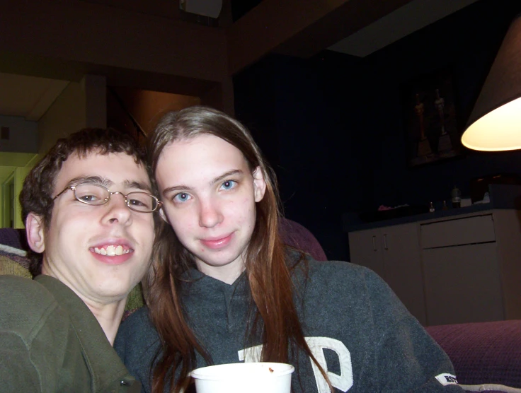 a couple holding a coffee cup smiling at the camera