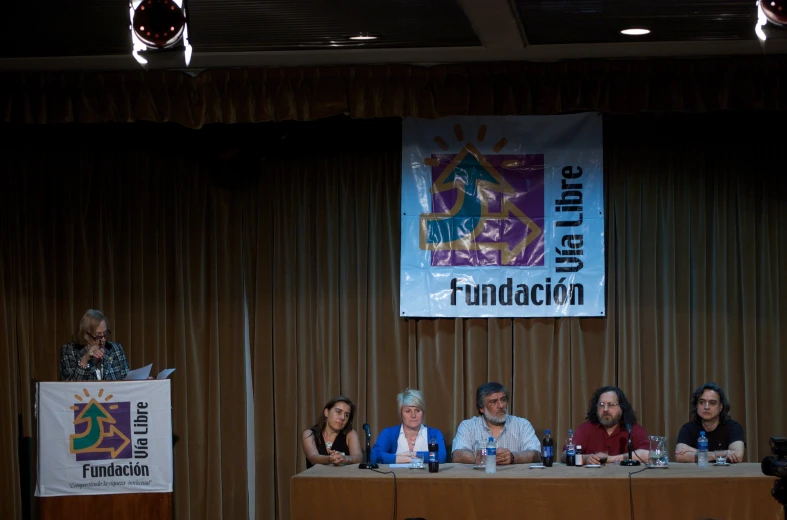 a group of people sit at a podium in front of a banner