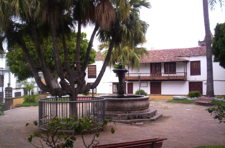 a large white house with a garden area and trees around it