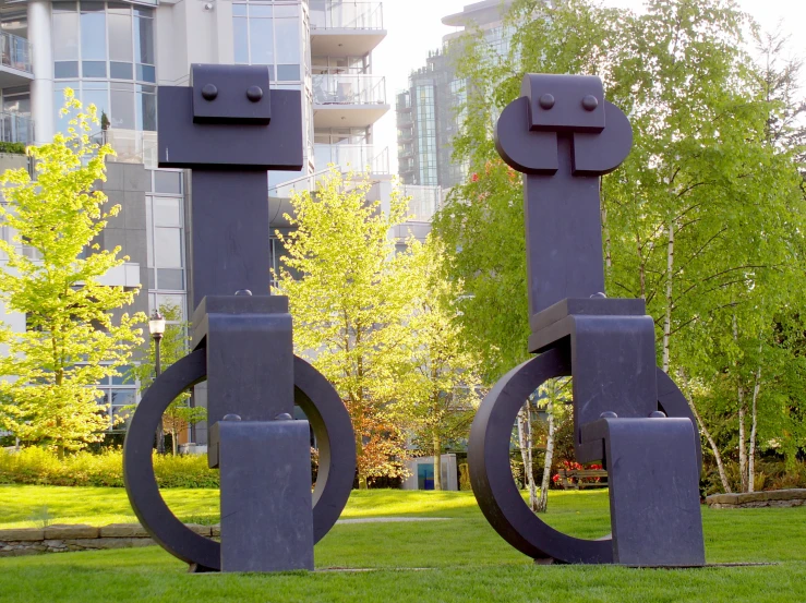 two large metal structures on the grass in front of buildings