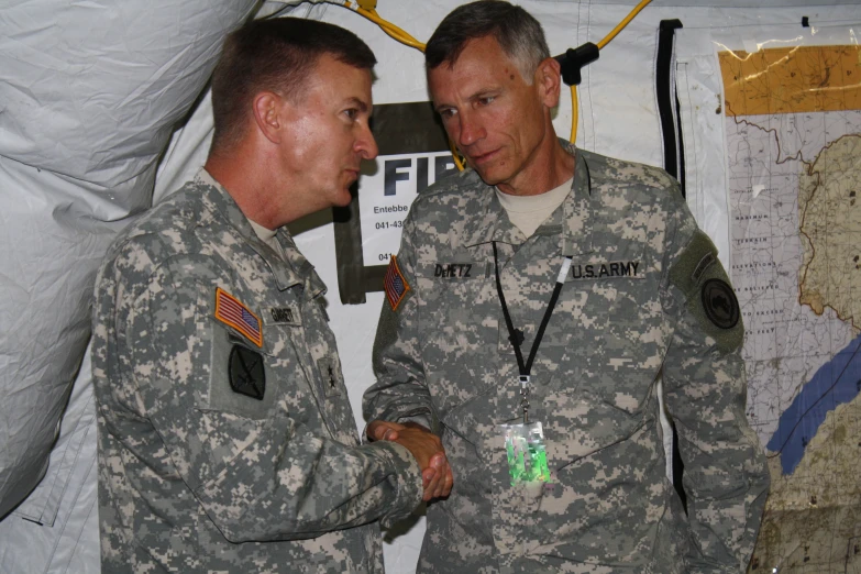 two soldiers shake hands over a wall with other things