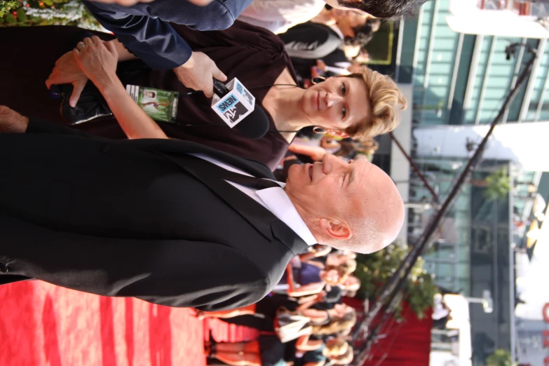 an old man talking to someone on a red carpet