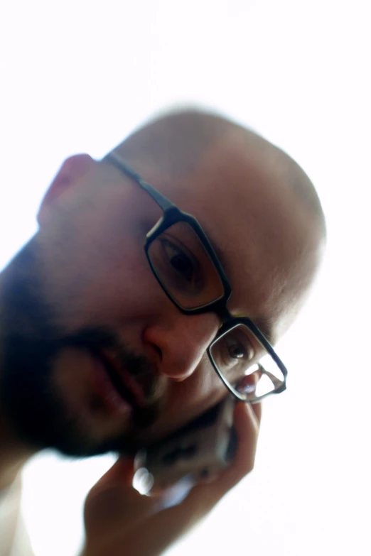 a close up of a man wearing glasses and talking on a cellphone