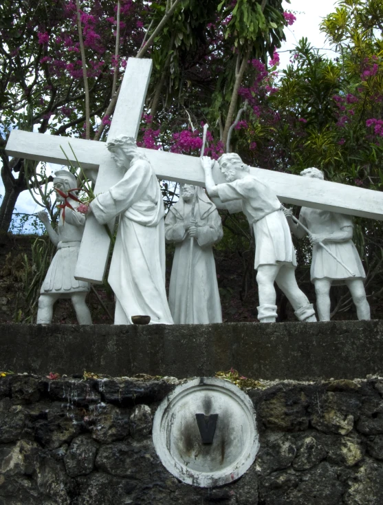a white statue of some people carrying a cross