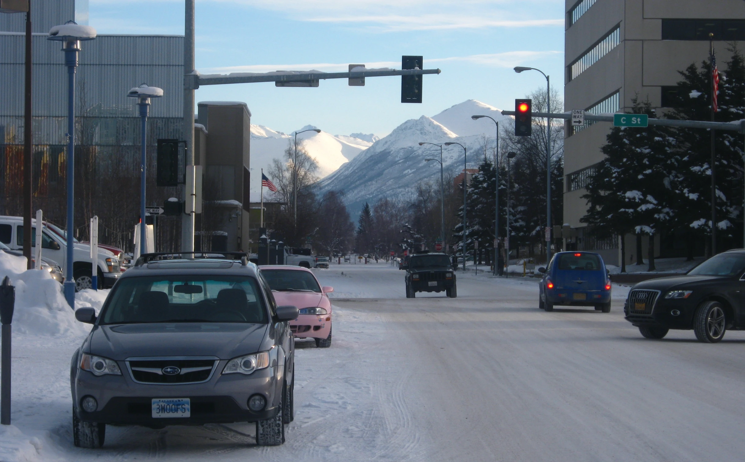 many cars in snow parked at the street light