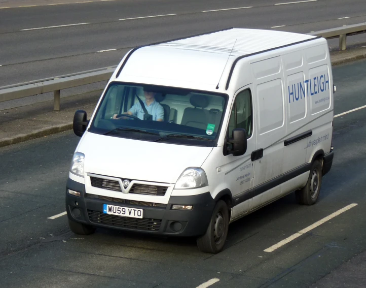 a van traveling down a road next to an overpass