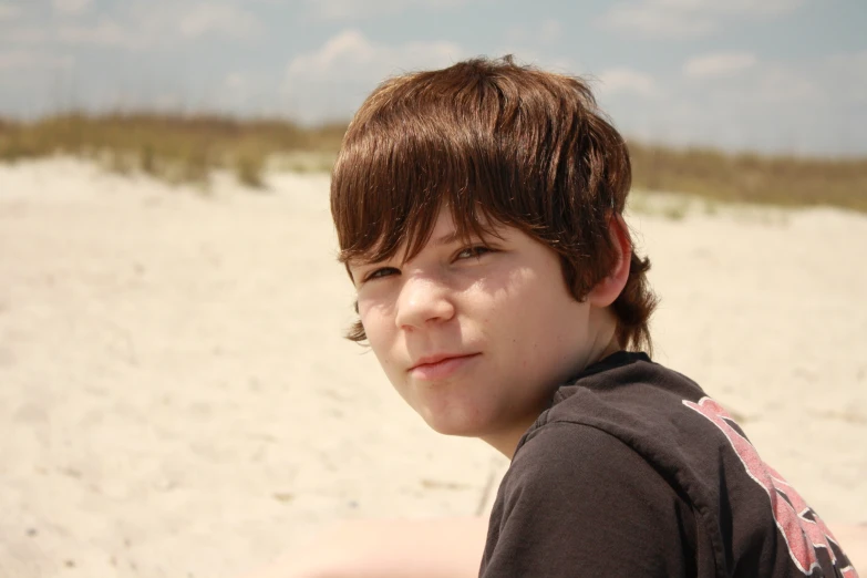 a child wearing a brown shirt and standing on a beach