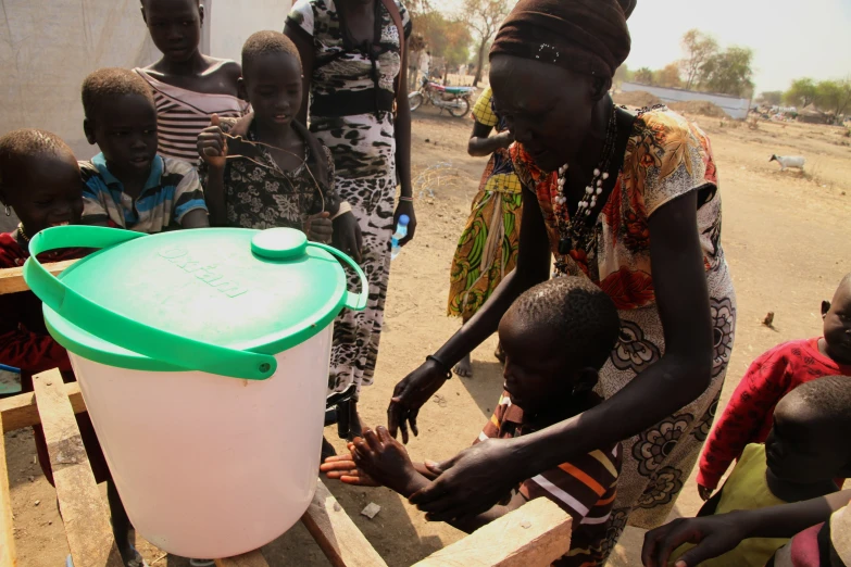 a group of people gather around a plastic container