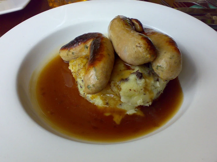 food items, including meats and sauce on white plate