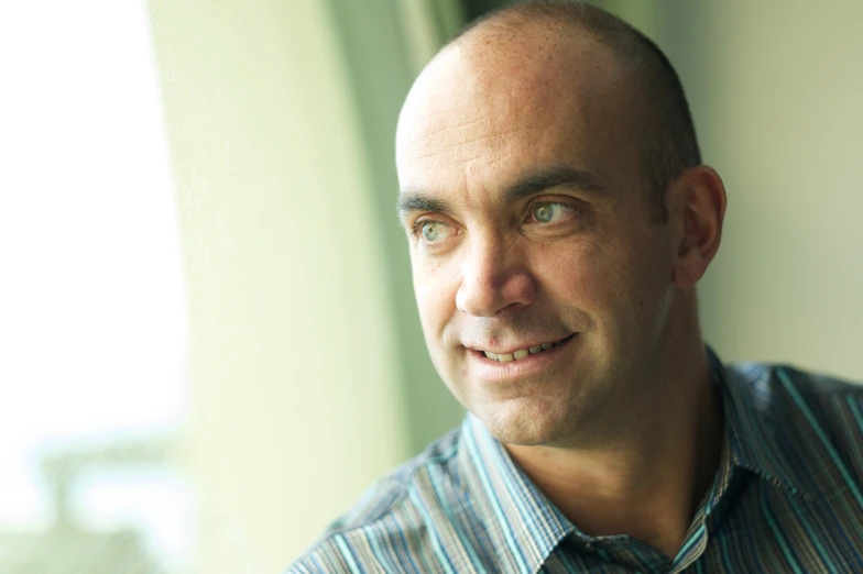 a man looks away while standing by a window