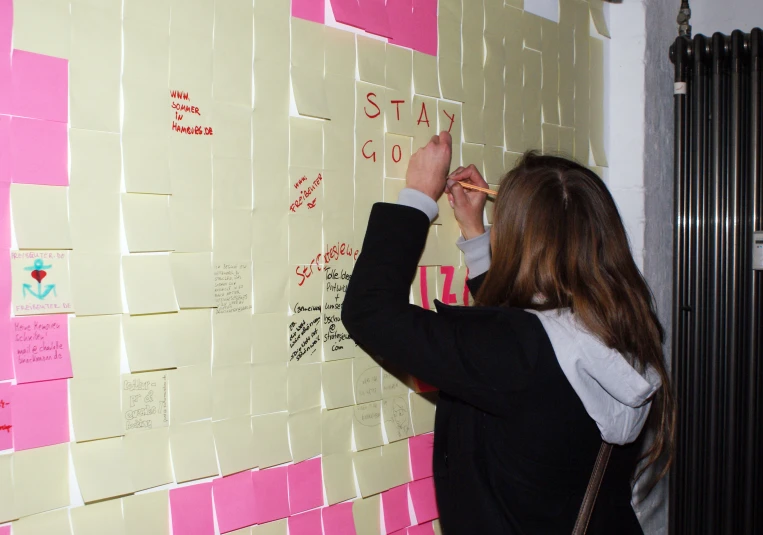 a person is writing on the pink sticky notes