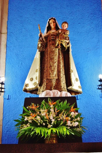statue of mary on a pedestal in front of a wall