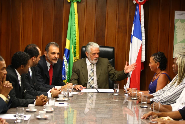 there is a man sitting in front of a large table surrounded by other people