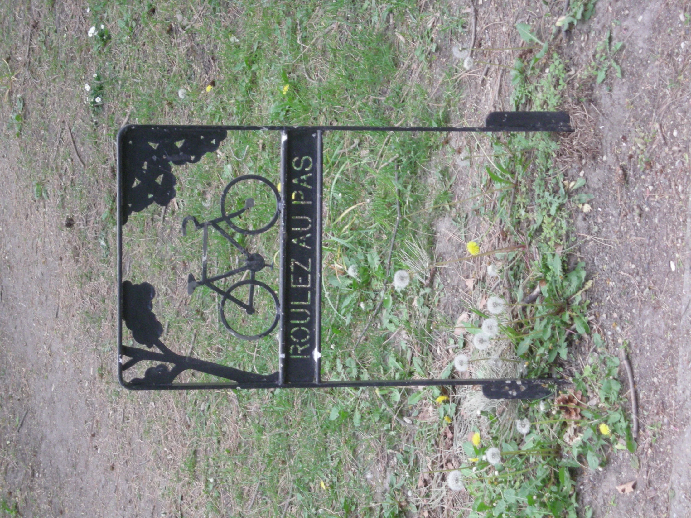 the shadow of a bike is cast in the ground next to a sign