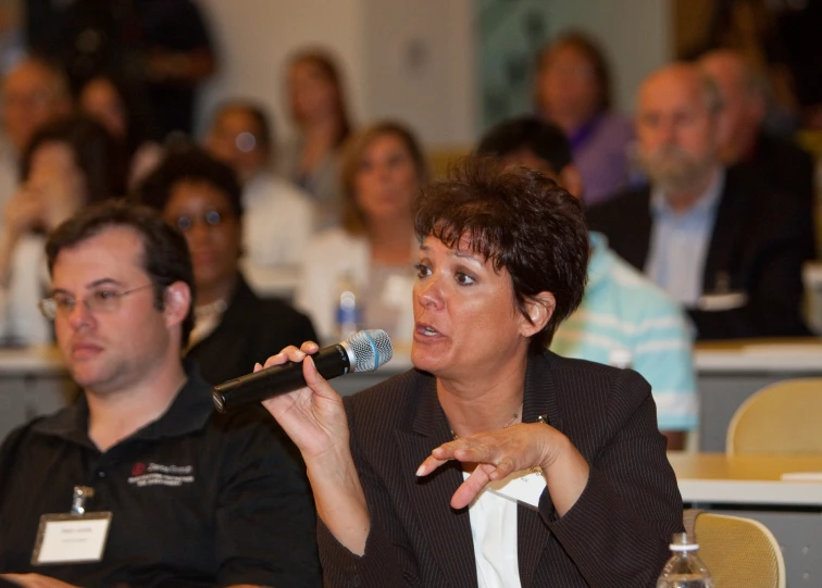 a woman speaking into a microphone in front of people