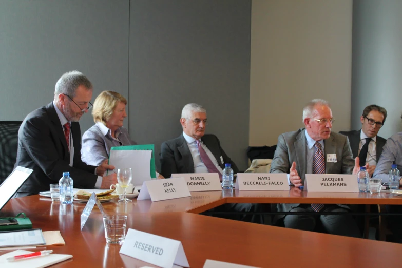 five business people sitting at a conference table with cards in their hands