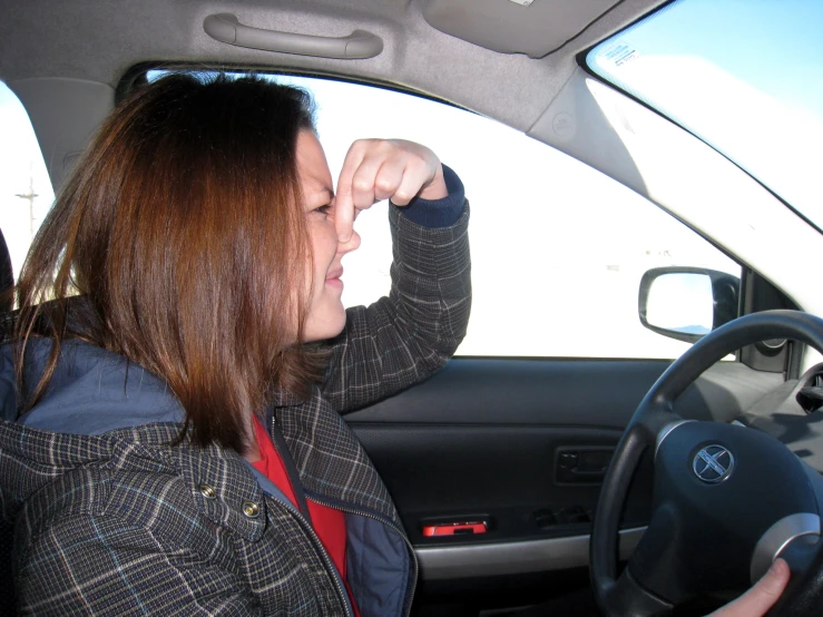 there is a woman driving a car and she has one hand in her head