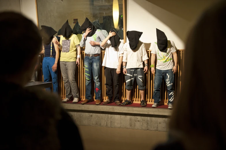 a group of young men with face masks standing behind a fence