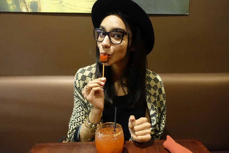 a woman eating noodles and drinking a beverage