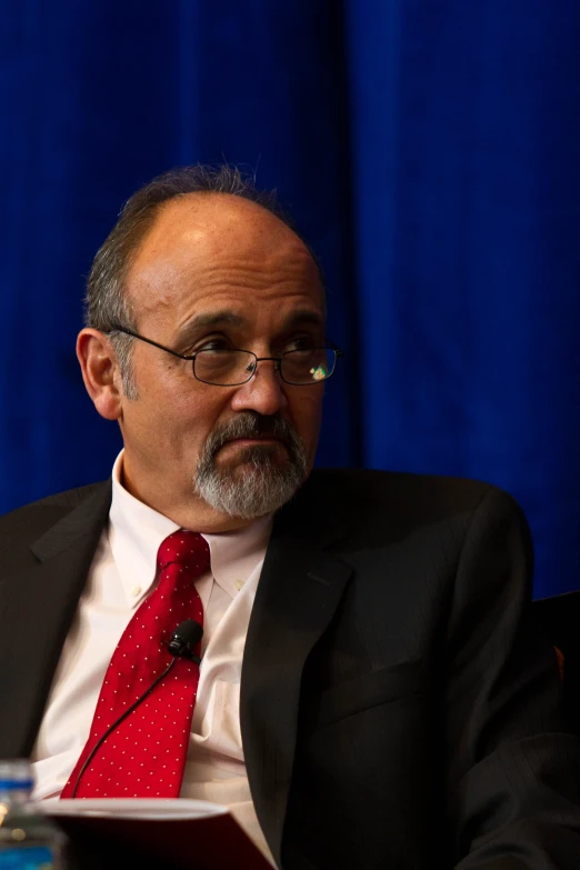 a bald man in a suit speaking into microphone