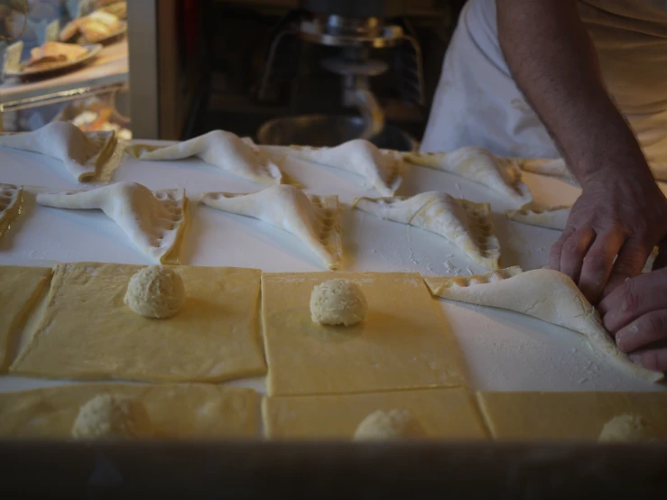 a chef places toppings on the top of dough