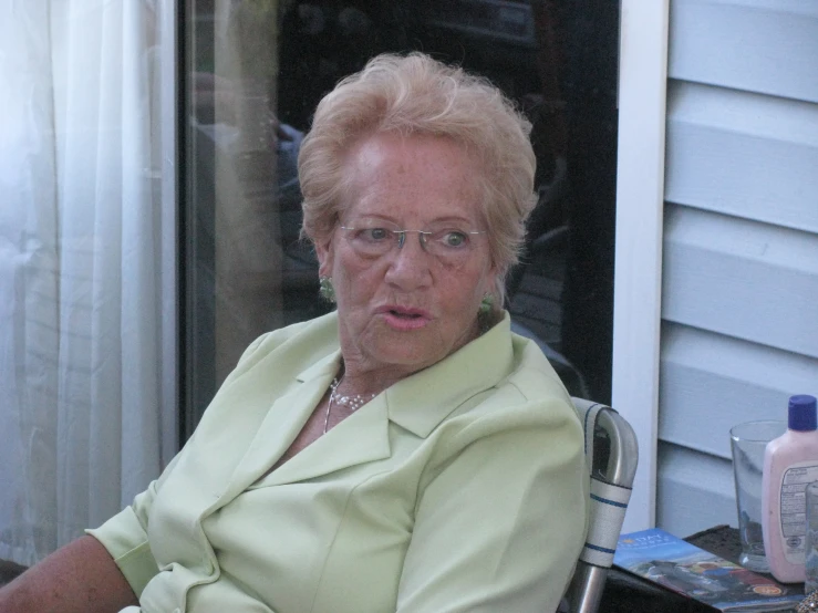 an older woman in glasses sits at a desk