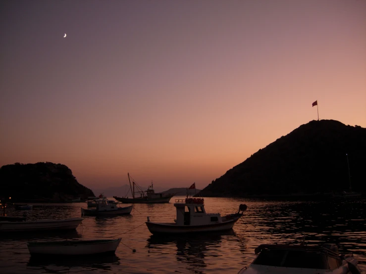 three boats at rest in the bay during sunset